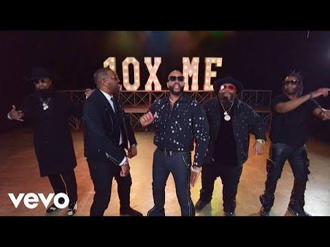 Five male performers stand on a dimly lit stage with a bright '40X ME' sign behind them; Vevo logo is in the lower-left corner.