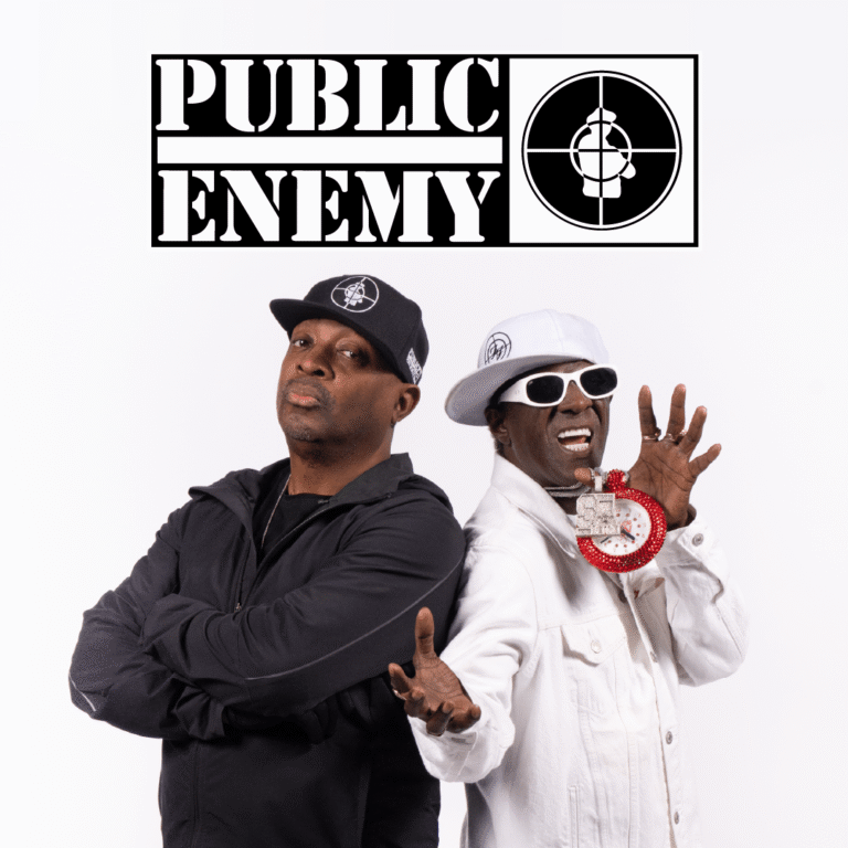 Public Enemy logo overhead; two men pose back-to-back, one in black with cap, the other in white wearing sunglasses and a red clock pendant while extending hands